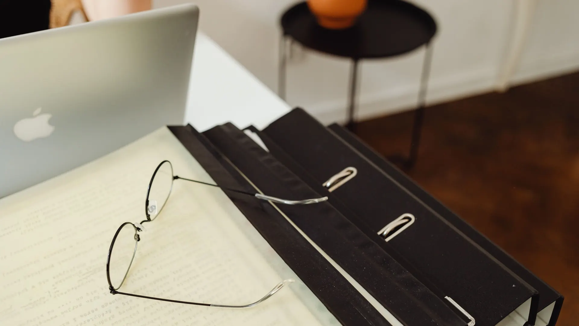 Classeurs et documents sur un bureau, à côté d'un ordinateur portable
